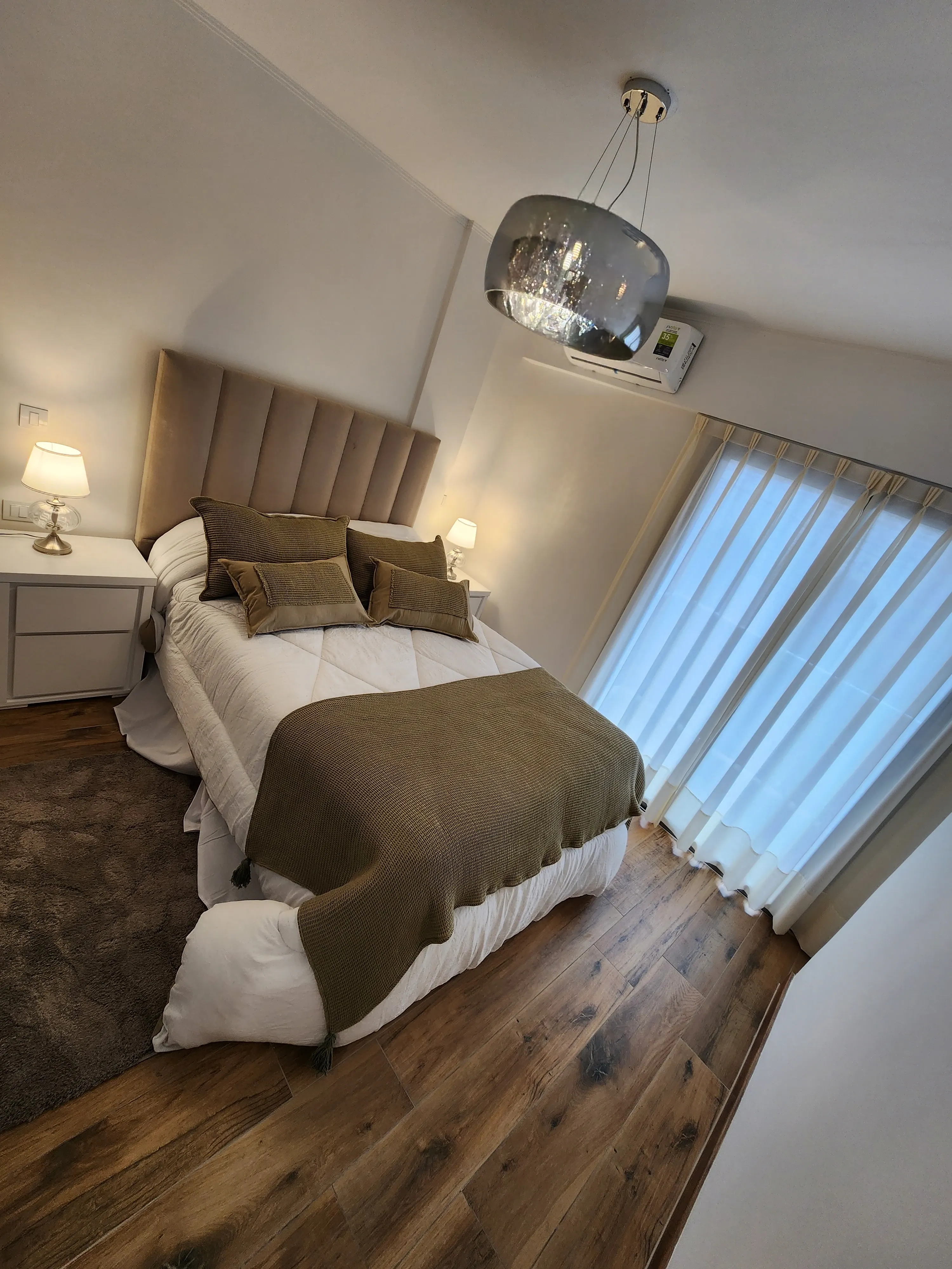 Dormitorio con cama doble, mesa de luz y acceso a balcón
